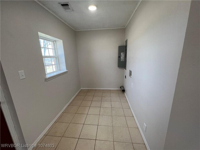 clothes washing area with crown molding, light tile patterned floors, a textured ceiling, and electric panel