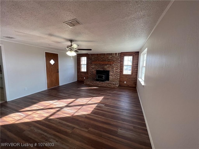 unfurnished living room featuring a textured ceiling, ceiling fan, crown molding, dark hardwood / wood-style floors, and a wood stove