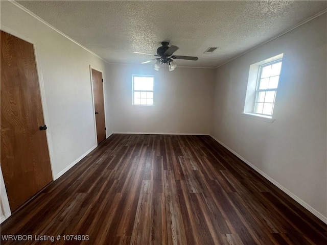 spare room with a textured ceiling, ceiling fan, dark hardwood / wood-style flooring, and plenty of natural light