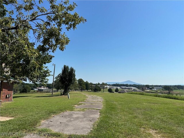 view of property's community with a mountain view, a yard, and a rural view