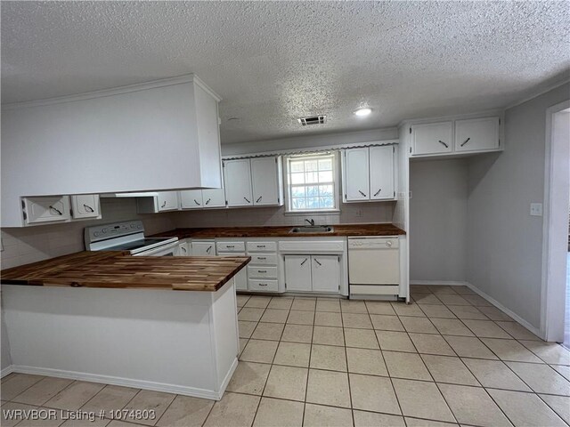 kitchen with butcher block counters, white appliances, sink, kitchen peninsula, and white cabinetry