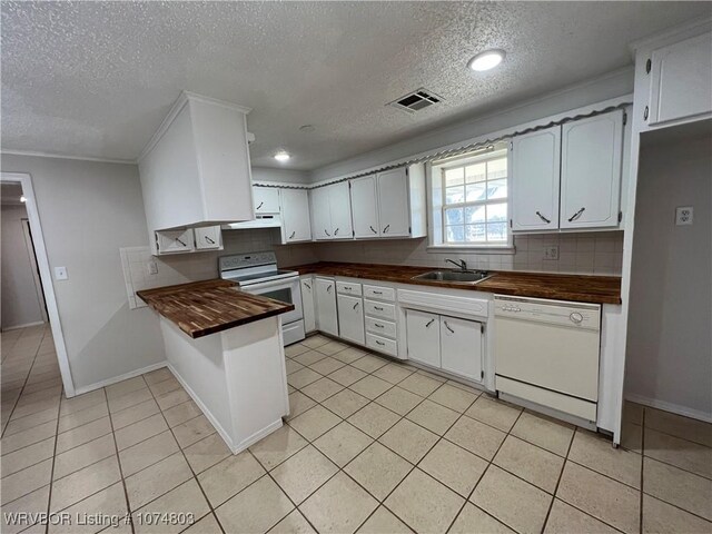 kitchen with butcher block counters, white appliances, backsplash, sink, and white cabinetry