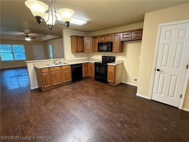 kitchen with baseboards, brown cabinetry, a sink, a peninsula, and black appliances