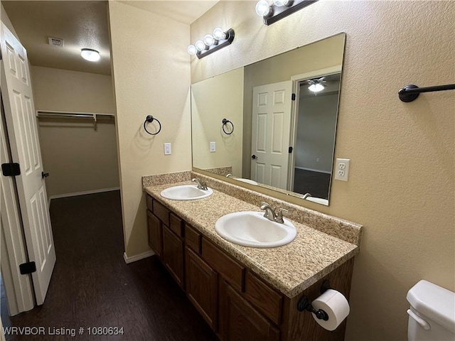 full bathroom featuring a sink, toilet, visible vents, and wood finished floors