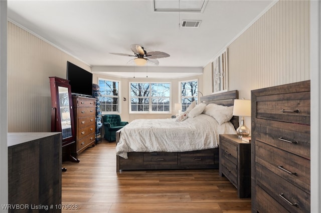 bedroom with visible vents, ornamental molding, a ceiling fan, and wood finished floors