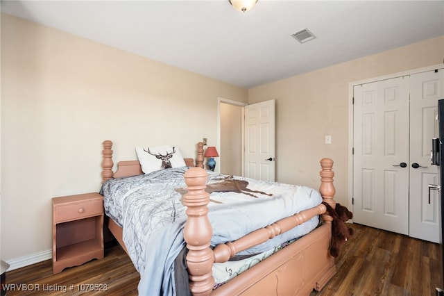 bedroom featuring dark wood finished floors, baseboards, visible vents, and a closet