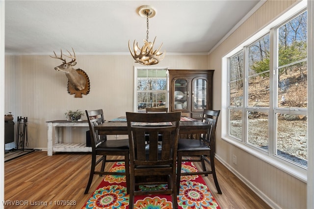 dining room with an inviting chandelier, crown molding, and wood finished floors