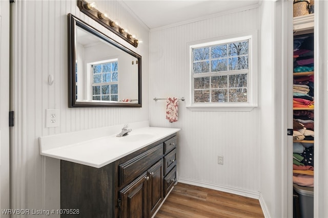 bathroom featuring vanity, crown molding, wood finished floors, and baseboards