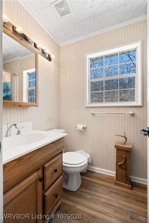 bathroom with vanity, wood finished floors, visible vents, ornamental molding, and toilet