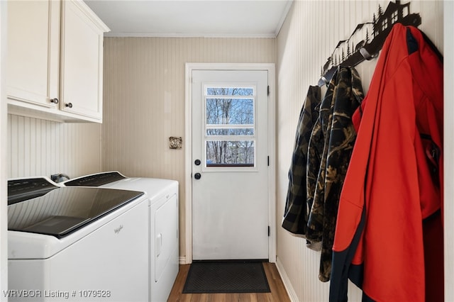 clothes washing area with washer and dryer, wood finished floors, cabinet space, crown molding, and baseboards