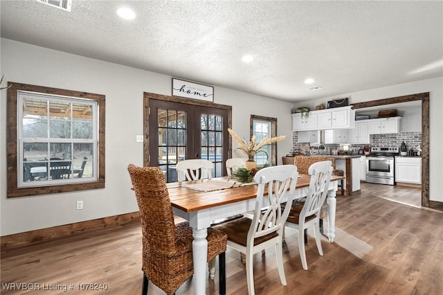 dining room featuring french doors, a textured ceiling, and hardwood / wood-style flooring