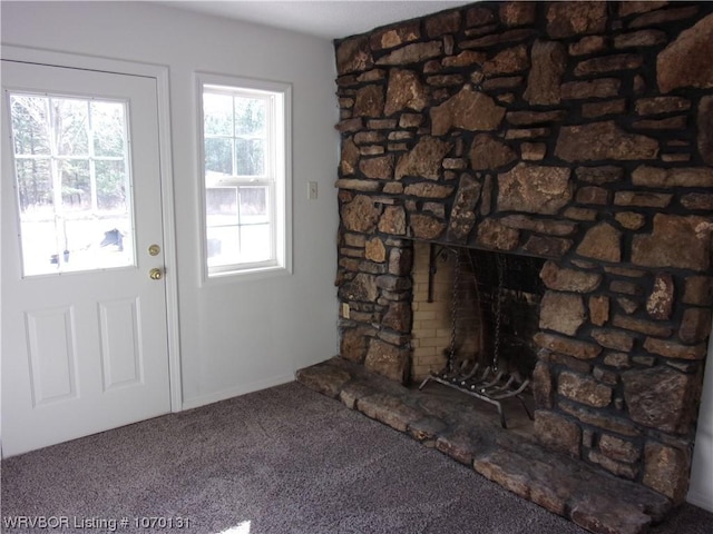 doorway to outside with carpet flooring and a stone fireplace