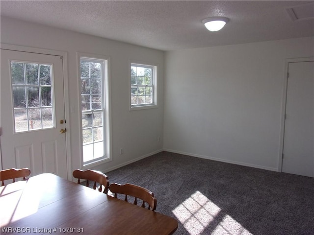 unfurnished dining area with dark colored carpet and a textured ceiling