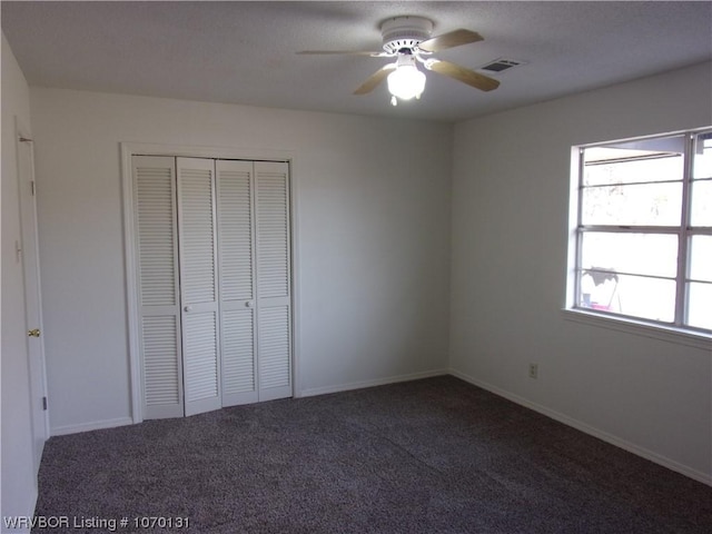 unfurnished bedroom featuring ceiling fan, a closet, and dark colored carpet