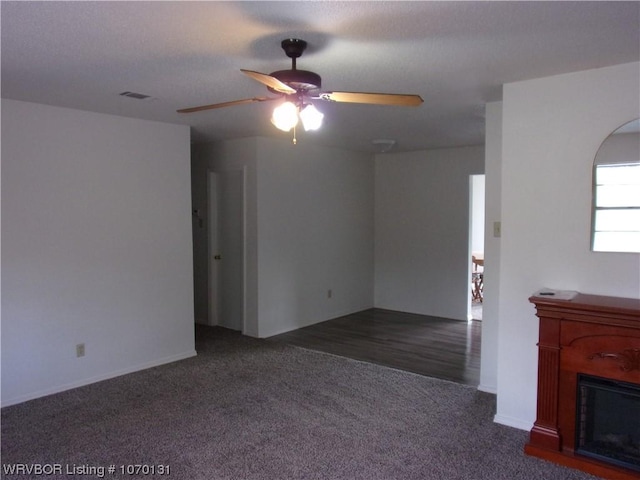 unfurnished living room featuring ceiling fan and dark carpet