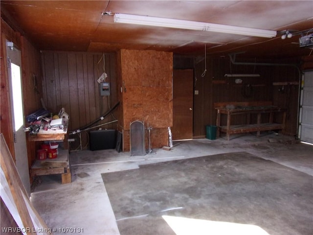 garage featuring electric panel, wooden walls, and a garage door opener