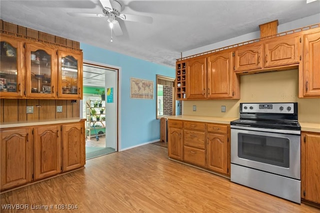 1310 Pigeon Creek Rd, Mountainburg, AR 72946 - kitchen featuring stainless steel range with electric stovetop, light countertops, light wood-style floors, ceiling fan, and brown cabinetry