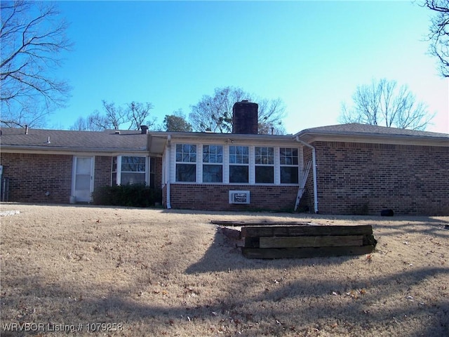 rear view of house with brick siding and a chimney