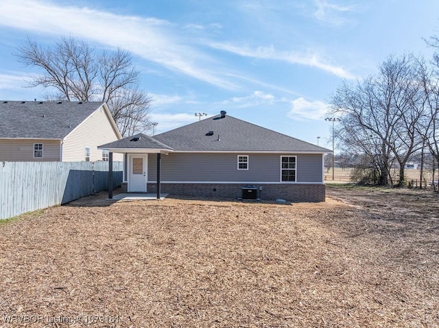 back of house with brick siding, a shingled roof, fence, and central air condition unit