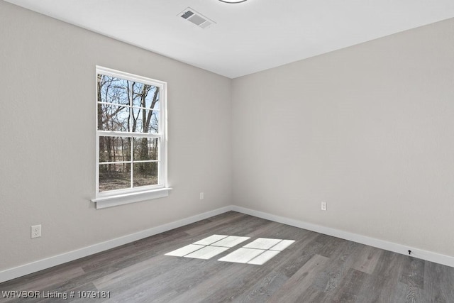 unfurnished room with baseboards, visible vents, and dark wood-type flooring