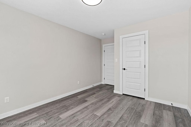 unfurnished room with baseboards and wood finished floors