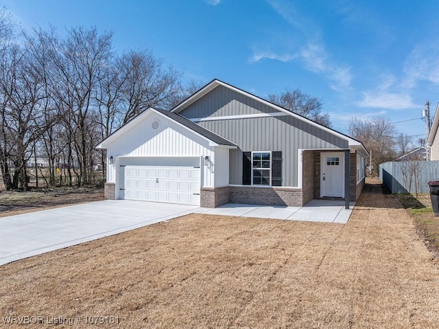 view of front of home with brick siding, an attached garage, fence, driveway, and a front lawn