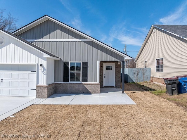 view of front of home featuring a garage, fence, and brick siding