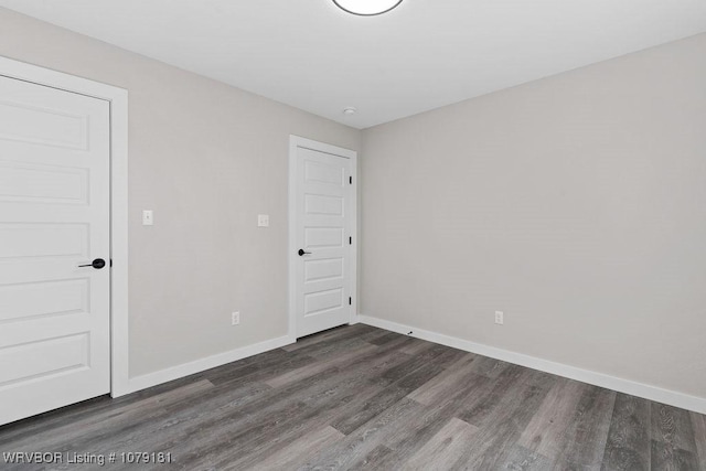 empty room featuring dark wood-style floors and baseboards