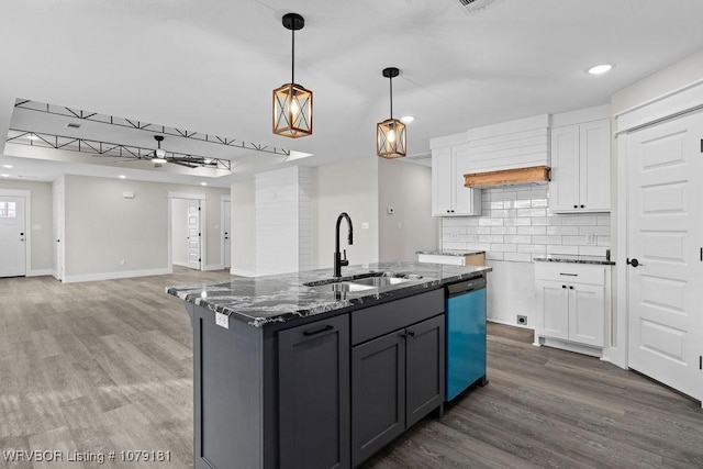 kitchen featuring white cabinets, dark stone countertops, hanging light fixtures, a sink, and stainless steel dishwasher