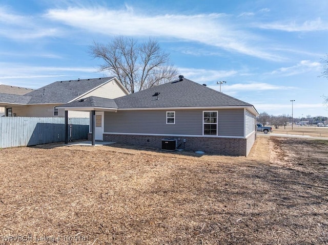 back of house with roof with shingles, fence, central AC, and brick siding