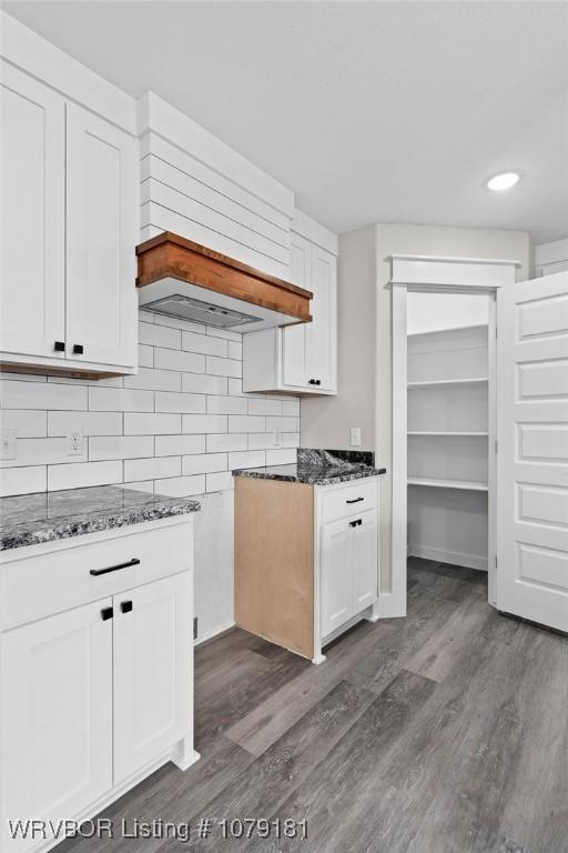 kitchen with dark stone counters, dark wood finished floors, and white cabinetry