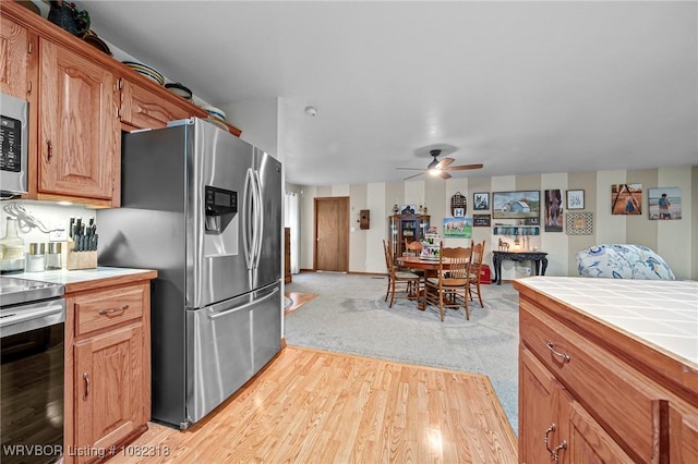 106078 S 4715th Rd, Muldrow, OK 74948 - kitchen with stainless steel appliances, tile countertops, ceiling fan, and light wood-style floors