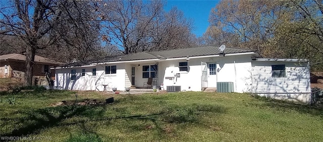 rear view of property with cooling unit and a yard