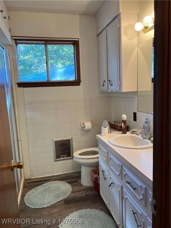 bathroom with vanity, toilet, wood-type flooring, and tile walls