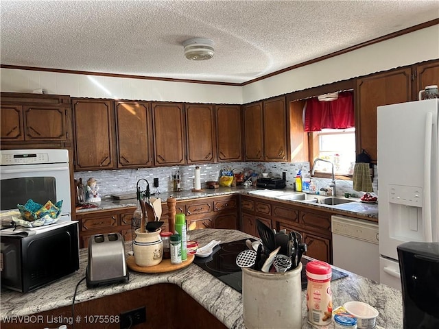 kitchen with a textured ceiling, white appliances, dark brown cabinets, and sink