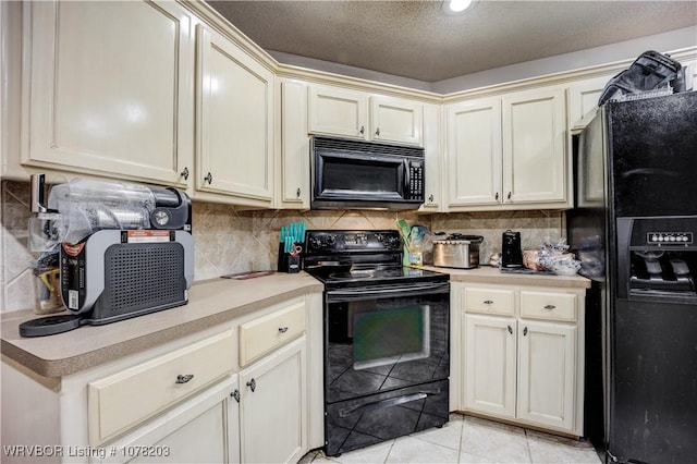 kitchen featuring tasteful backsplash, light tile patterned floors, black appliances, and cream cabinetry