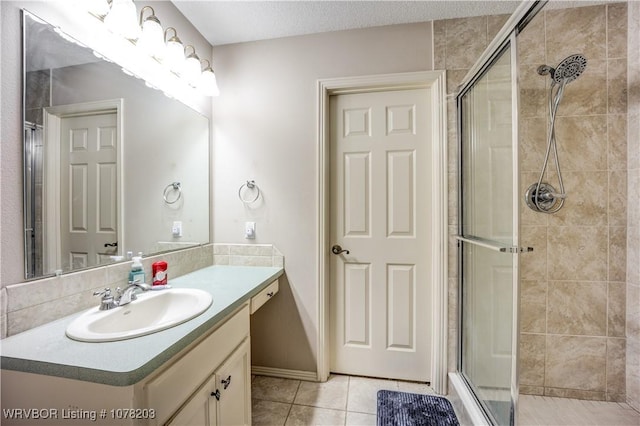 bathroom with a textured ceiling, tile patterned flooring, vanity, and an enclosed shower