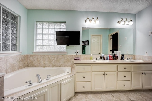 bathroom featuring a bathing tub, tile patterned flooring, vanity, and a textured ceiling