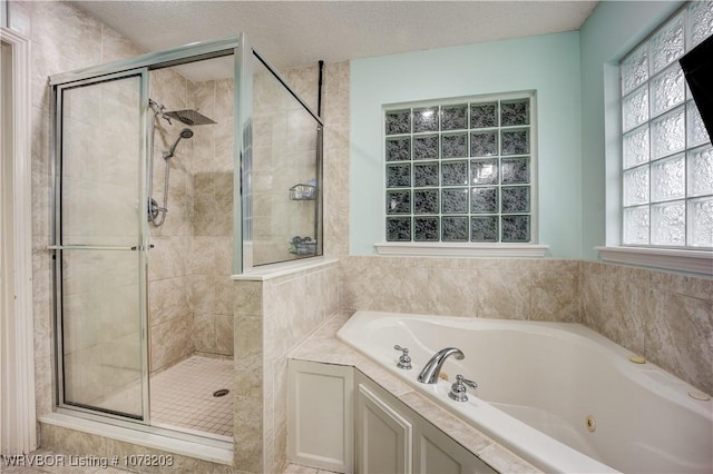 bathroom featuring a textured ceiling and shower with separate bathtub