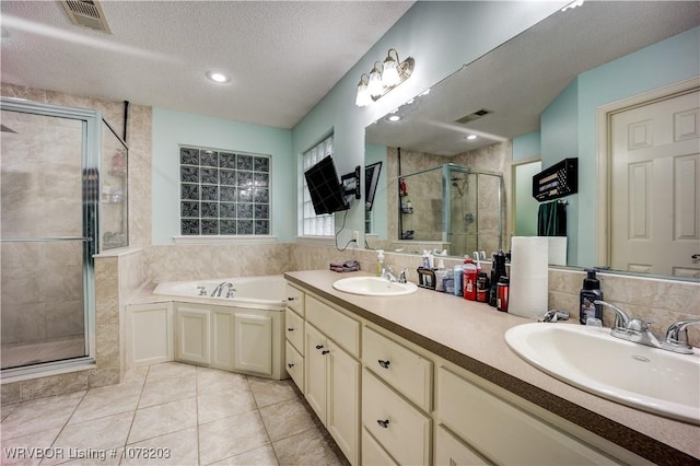 bathroom featuring tile patterned floors, vanity, shower with separate bathtub, and a textured ceiling