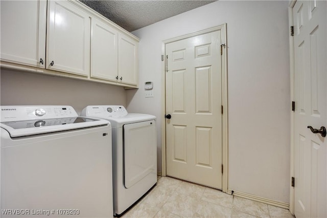 clothes washing area featuring washing machine and dryer, cabinets, and a textured ceiling