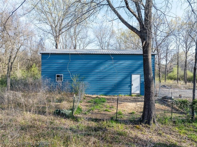 view of side of property featuring metal roof, an outdoor structure, and a pole building