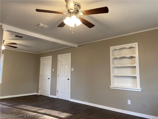 spare room featuring a textured ceiling, built in features, dark wood-type flooring, and crown molding