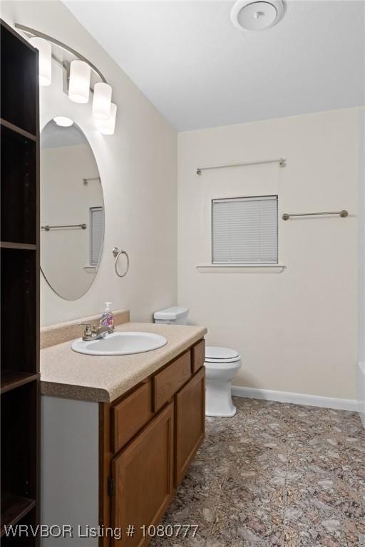 bathroom featuring vanity, toilet, and baseboards