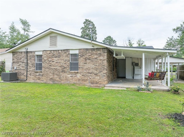 rear view of property featuring a lawn, brick siding, and central AC unit