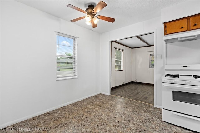 kitchen featuring white gas range, ceiling fan, under cabinet range hood, brown cabinetry, and baseboards