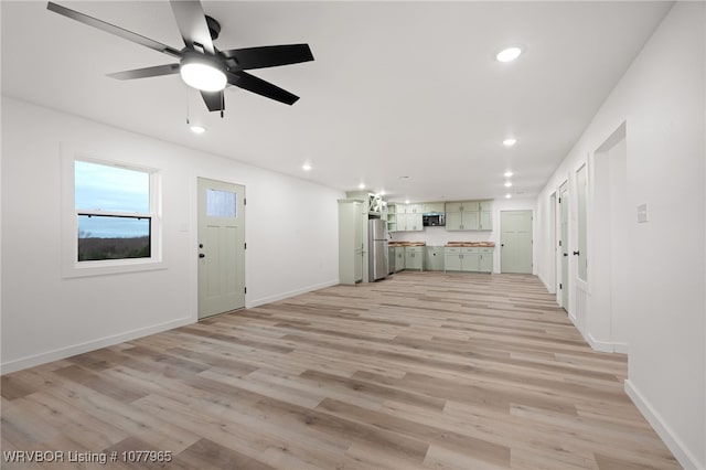 unfurnished living room with ceiling fan and light wood-type flooring