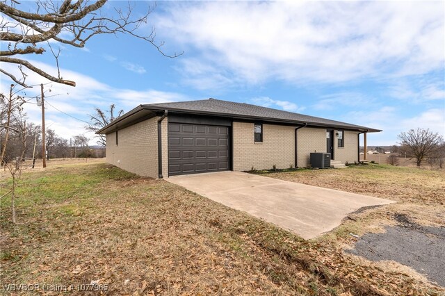 view of side of property featuring a garage, central AC unit, and a lawn