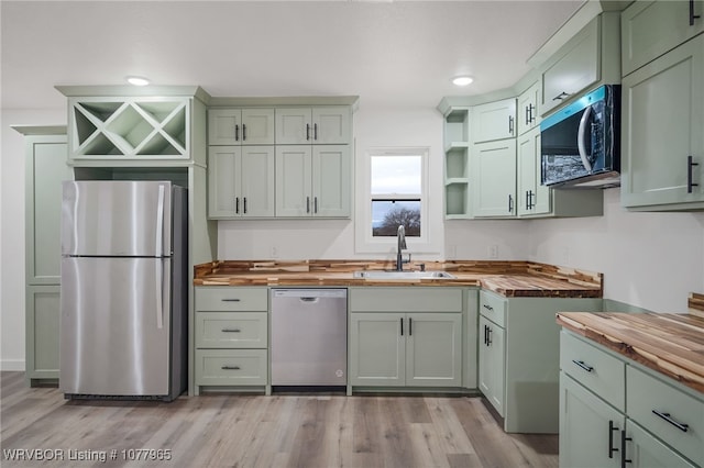 kitchen featuring sink, stainless steel appliances, light hardwood / wood-style flooring, butcher block countertops, and green cabinetry