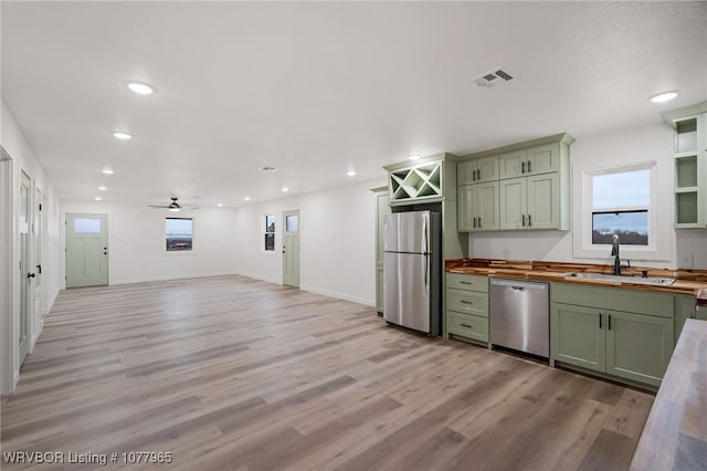 kitchen featuring wooden counters, green cabinets, sink, light hardwood / wood-style floors, and stainless steel appliances